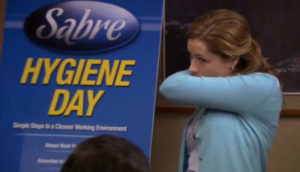 Still image of Jenna Fischer as Pam Beesley from the TV show the Office demonstrating a "vampire cough/sneeze" and covering her nose & mouth with her elbow.
